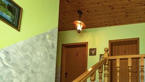 Een trap met houten balustrades die leidt naar een plateau met twee houten deuren, waarvan er één het nummer 1 heeft.