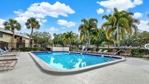 Una piscina con sillas de descanso y palmeras.
