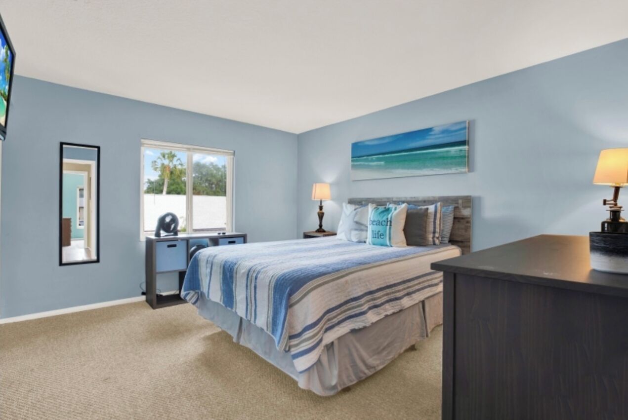 A bedroom with a bed, bedside tables, a desk, and a window.