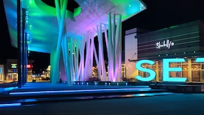 Un bâtiment moderne doté de structures verticales illuminées et d’un grand panneau lumineux représentant les lettres « SE ».