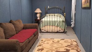 A bedroom with a bed, a couch, a lamp, and a rug.