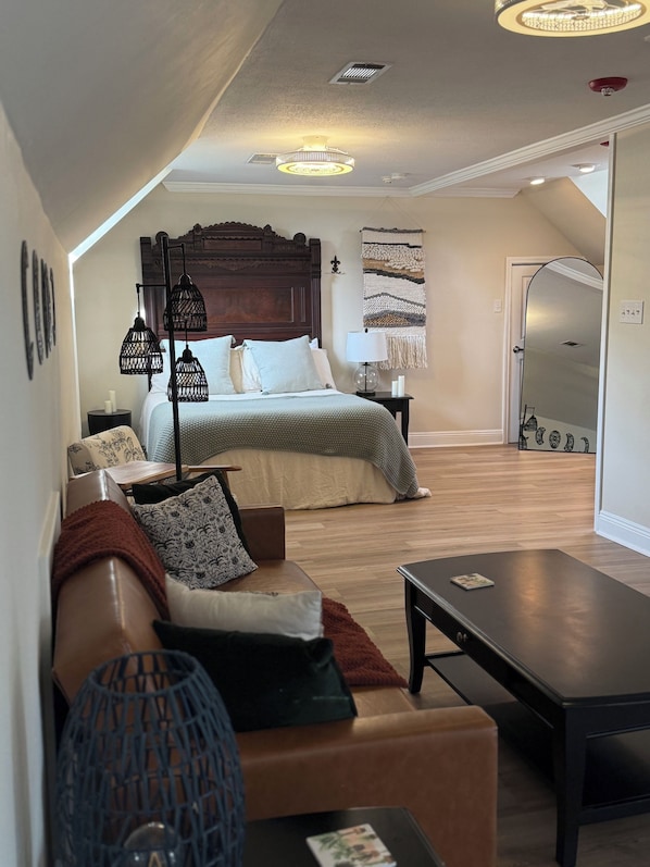 A bedroom with a wooden headboard, a bed with a green blanket, a nightstand with a lamp, and a wall-mounted tapestry. - Cozy loft in Olde Town Slidell (Slidell)