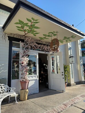 A storefront with a sign reading "Roots Coffee" and a large potted plant in front. - Cozy loft in Olde Town Slidell (Slidell)