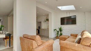 Ein modernes Wohnzimmer mit zwei Ledersofas, einem flachbildfernseher an einer weißen Ziegelwand und einem Oberlicht.