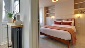 Ein Schlafzimmer mit Bett, Nachttischen, einem Heizkörper, einem Spiegel und einem Regal mit Dekoration.