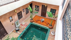A courtyard with a swimming pool, potted plants, and traditional Moroccan tiles. - Riad Lalla Fatima  (Marrakech)
