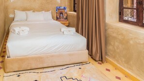 A bedroom with a bed, a headboard, a window with curtains, and a wall-mounted artwork. - Riad Lalla Fatima  (Marrakech)