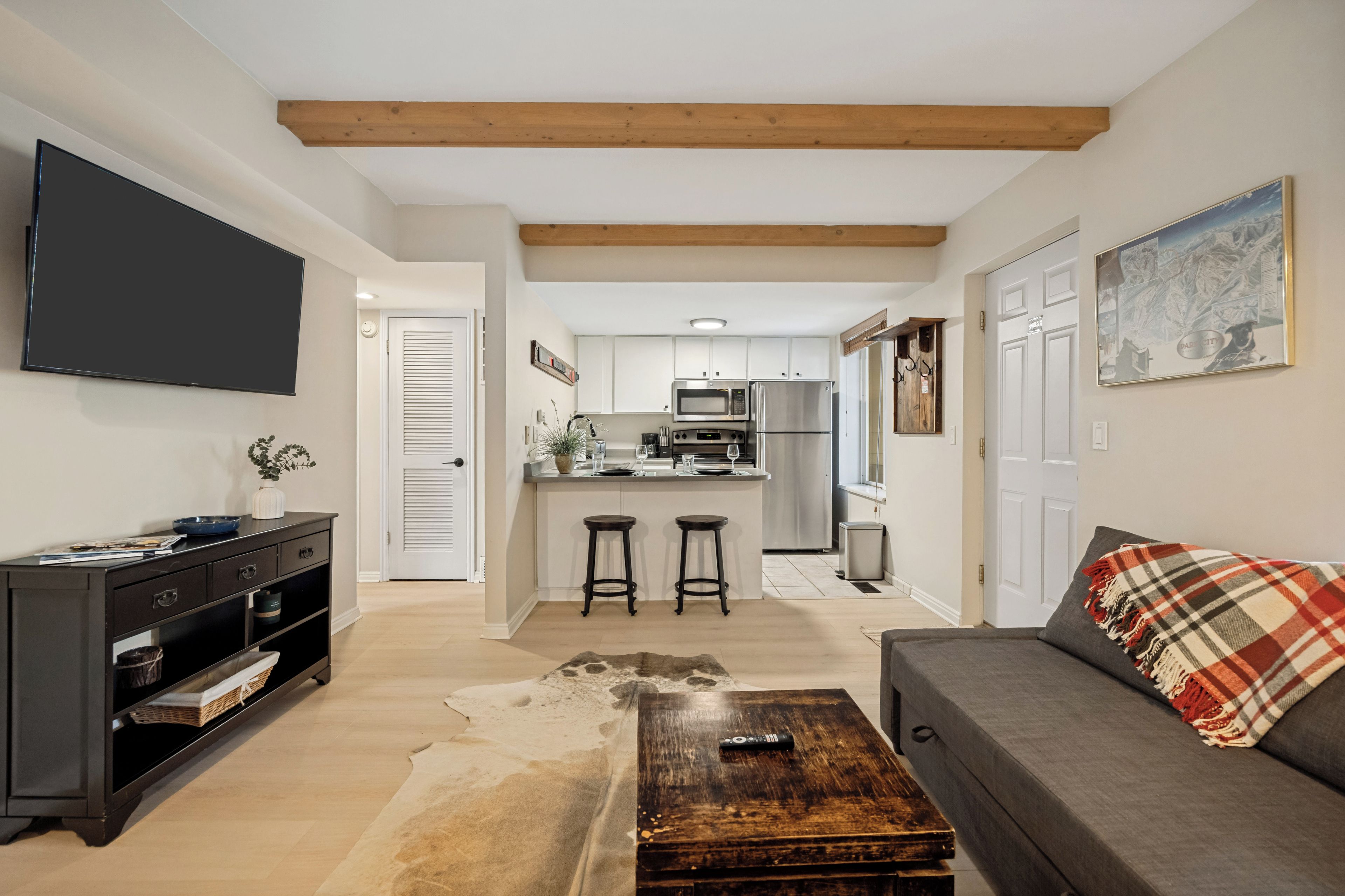 A modern apartment with a kitchen, living room, and a TV mounted on the wall.
