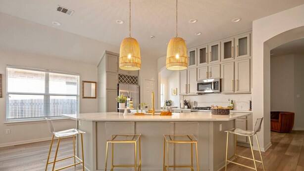 Uma cozinha moderna com ilha central, luminárias pendentes e banquetas.
