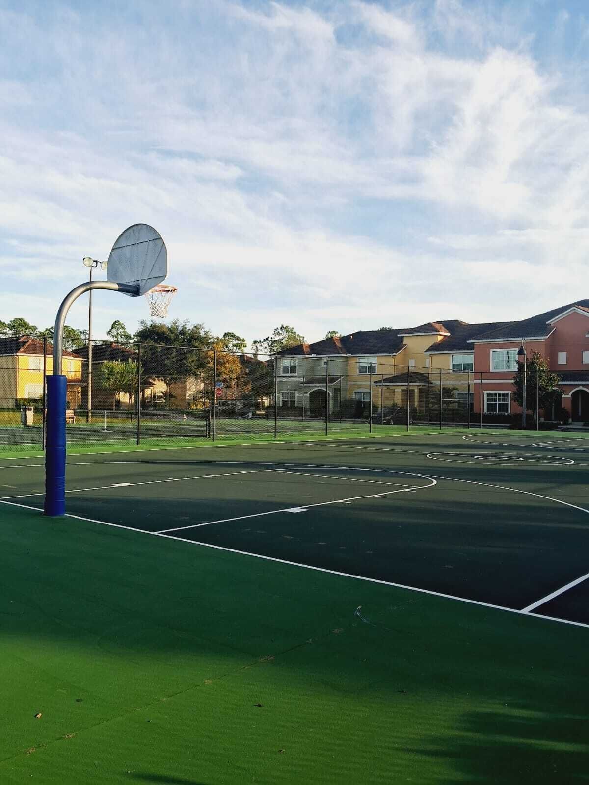 An outdoor basketball court with a metal hoop and a blue post.