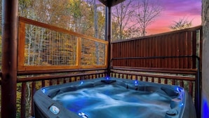 Ein Whirlpool auf einer Holzterrasse mit Blick auf Herbstbäume.