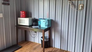 A compact kitchenette with a microwave, coffee maker, and a small table. - Friesian Cabin (Heavener)