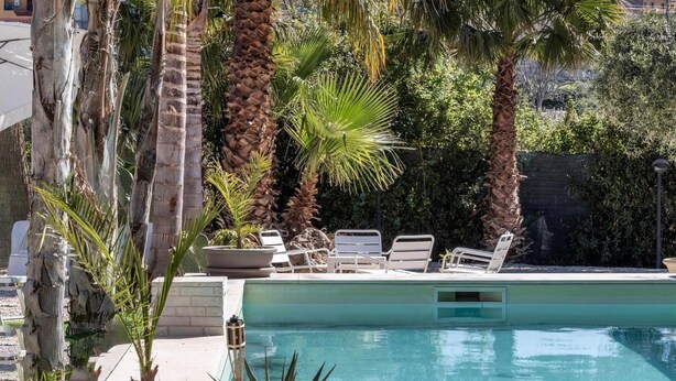 A pool area with lounge chairs and palm trees. - Rifugio Del Sole Villa con Piscina (Noto)
