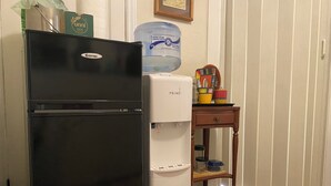 A black refrigerator and a white mini-fridge in a room with a wooden side table holding colorful cups and a water dispenser. - South Seattle, Free Parking, Private Entrance and 3/4 Bath, Q Bed, Free Laundry. (Seattle)