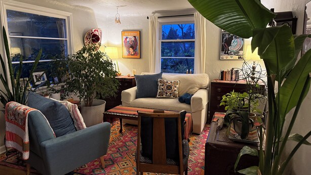 A cozy living room with a sofa, armchair, and a coffee table, surrounded by various plants and a colorful rug. - South Seattle, Free Parking, Private Entrance and 3/4 Bath, Q Bed, Free Laundry. (Seattle)