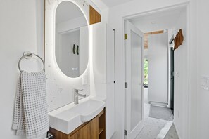 A modern bathroom with a large mirror, a sink, and a towel rack. - Loft 5 - Designer Cabin, Walls of Light, Sauna (West Windsor)