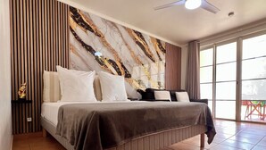 Een moderne slaapkamer met een groot bed, een plafondventilator en uitzicht op de omgeving door een schuifdeur.