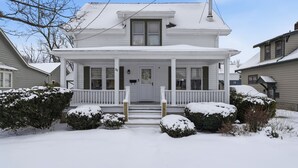 A two-story white house with a front porch, a chimney, and a snow-covered lawn. - Four Seasons Haven (Angola)