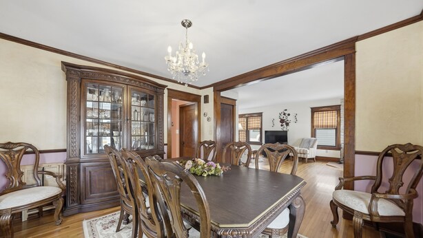 A dining room with a large wooden table, ornate chairs, a chandelier, and a cabinet with glass doors. - Four Seasons Haven (Angola)