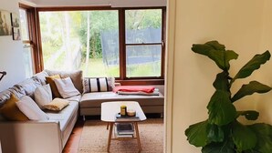 Una sala de estar con sofá, una mesa de centro y una planta grande.