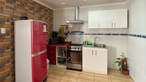 A compact kitchen with a refrigerator, stove, oven, and sink. - Spacious and Charming Apartment in Iquique. (Iquique)