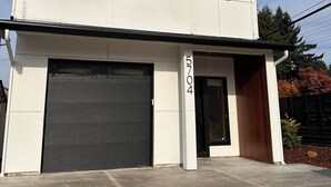 Une maison moderne à deux étages, dotée d’un garage, d’une porte d’entrée et d’une allée.