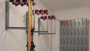 Una habitación con alfombra roja, un soporte para esquíes y un soporte de esquíes montado en la pared.