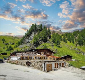 A mountain lodge with a sign reading 'CARPANNIA,' surrounded by lush green hills and a rocky mountain backdrop. - Capanna Bill (Rocca Pietore)