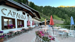 Un restaurante con terraza, mesas de madera y arreglos florales.