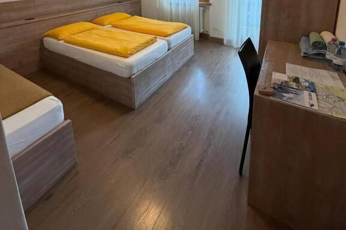 A room with two beds, a desk, a chair, and a window with curtains.