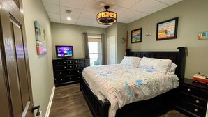 Un dormitorio con cama, cómoda y televisor sobre un mueble.