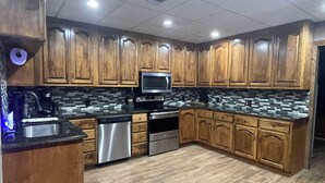 Una cocina moderna con armarios de madera, lavavajillas de acero inoxidable, microondas y salpicadero de azulejos.