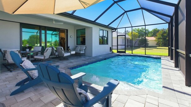 A modern outdoor pool area with a covered seating area and a view of the surrounding landscape. - Cape Luxe Canal Retreat - Saltwater Pool & Game Room & Kayaks (Cape Coral)