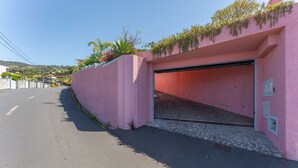 A pink building with a garage door, a paved road, and a clear sky. - FLH Funchal Studio Blue View Gardens (Funchal)