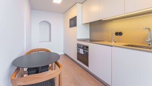 A compact kitchen with a microwave, oven, and sink, a small dining table, and a chair. - FLH Funchal Studio Blue View Gardens (Funchal)