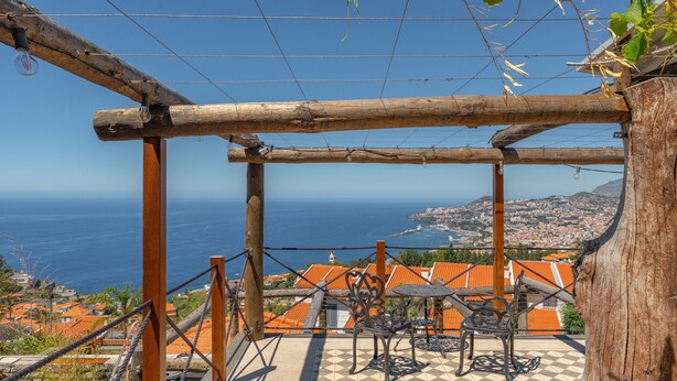 A terrace with a view of the sea, a table with chairs, and a wooden pergola structure. - FLH Funchal Studio Blue View Gardens (Funchal)