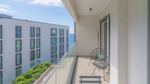 A balcony with a glass railing, two chairs, and a small garden area. - FLH Ocean View Escape at Acqua Residences (Funchal)