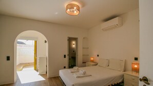 Un dormitorio con cama, mesitas de noche, un espejo y un equipo de aire acondicionado.