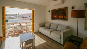 Una sala de estar con un sofá, una mesa de comedor con sillas, un cuadro y una lámpara.