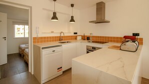 Una cocina moderna con armarios blancos, lavavajillas integrado y encimera de mármol.