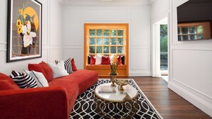 Ein Wohnzimmer mit einem roten Sofa, einem runden Couchtisch und einem großen gerahmten Kunstwerk an der Wand.