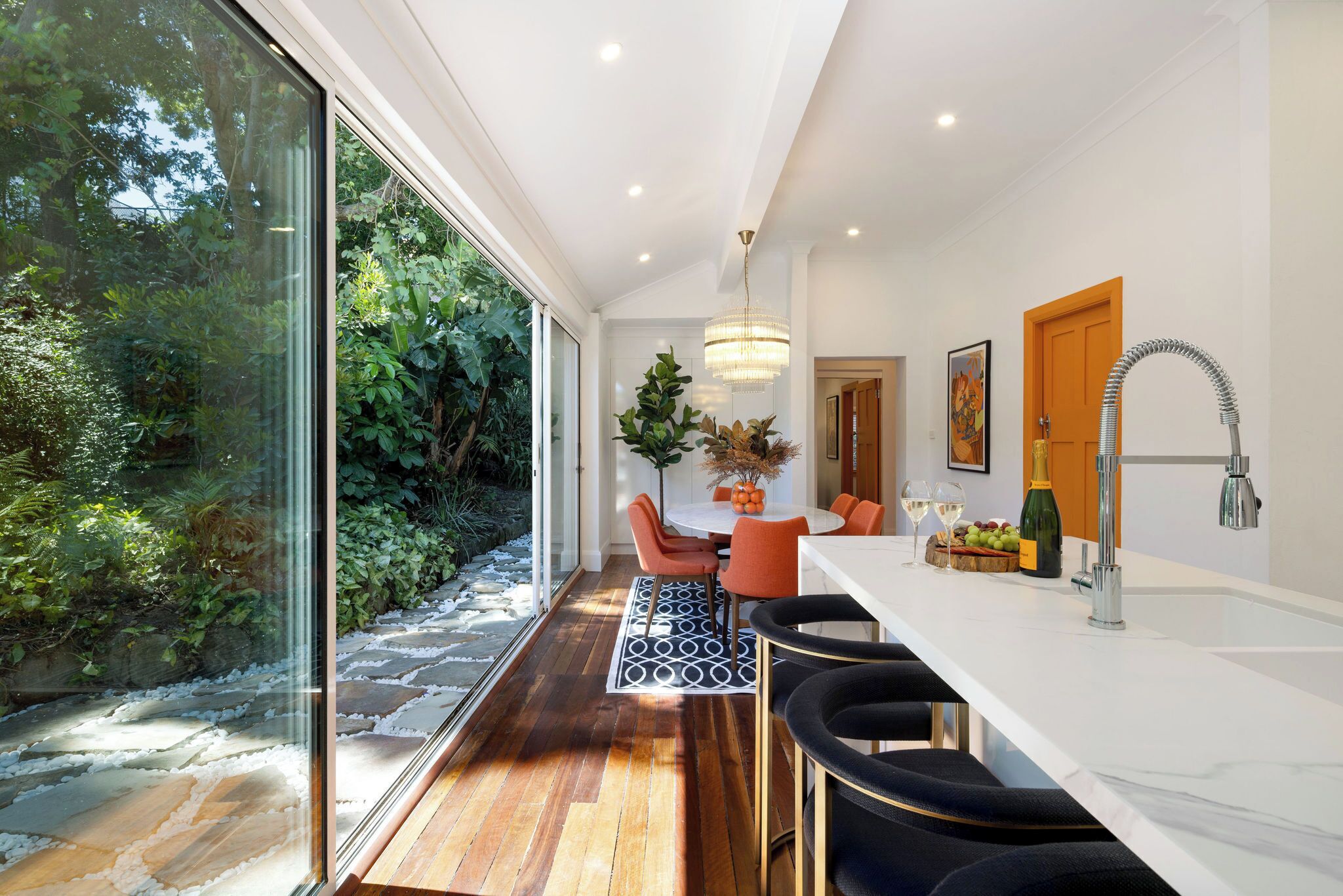 A modern kitchen with a marble countertop, a built-in oven, and a sink.