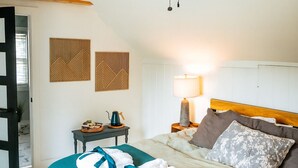 Habitació d'hotel amb llit, ventilador de sostre, tauleta de nit amb làmpada i paret amb panells decoratius.