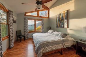 Ein Schlafzimmer mit Bett, Stuhl, Schreibtisch, Deckenventilator und einem Fenster mit Blick.