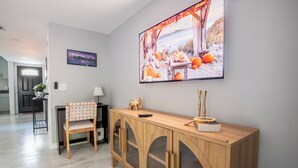 Un salon moderne avec une console en bois, un fauteuil et un grand tableau encadré accroché au mur.
