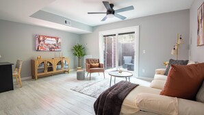 Un salon comprenant un canapé, une table basse, un meuble, un fauteuil et un ventilateur de plafond.