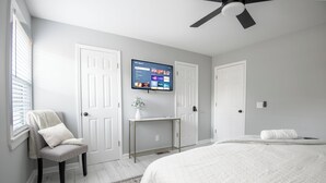 Une chambre à coucher comprenant un lit, une chaise, un bureau et un téléviseur fixé au mur.