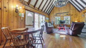 Un intérieur en bois comprenant une table à manger, des chaises, un canapé en cuir et un lustre.