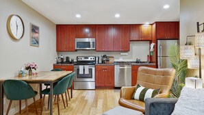 Una cocina moderna con armarios de madera, electrodomésticos de acero inoxidable y un comedor con sillas verdes.