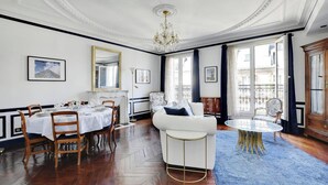 Een ruime kamer met een eethoek, een bank en een ronde tafel.